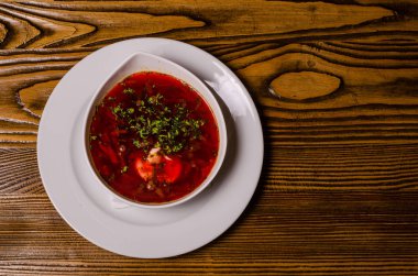 Çorba, ekşi kremalı borç, arka planda boncuk ve turşu. Borç beyaz bir tabakta, ekmek dilimleri ahşap bir kesme tahtasında, turşular ahşap bir tabakta..