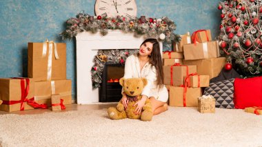 Noel süslemeli stüdyoda şöminenin yanında poz veren çekici esmer kadın.  