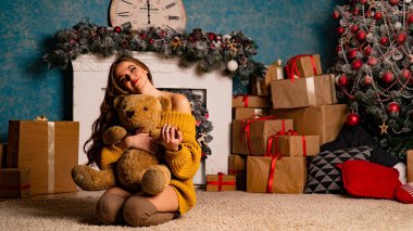 Noel süslemeli stüdyoda şöminenin yanında poz veren güzel esmer genç bir kadın. 