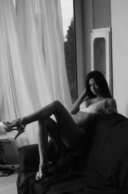 İç çamaşırlarıyla kanepede poz veren sevimli, çekici, çekici bir kızın portresi. 