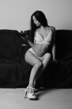 İç çamaşırlarıyla kanepede poz veren sevimli, çekici, çekici bir kızın portresi. 