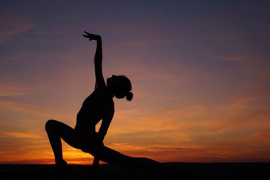 Dans eden dansçı gün batımına karşı havada yarılır.