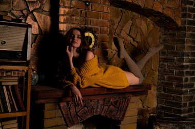 Şöminenin yanında oturan güzel kız. Noel için içi köknar dalları ve oyuncaklarla süslenmiş lüks bir iç mekan.