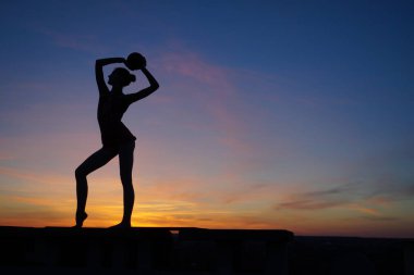 Dans eden dansçı gün batımına karşı havada yarılır.