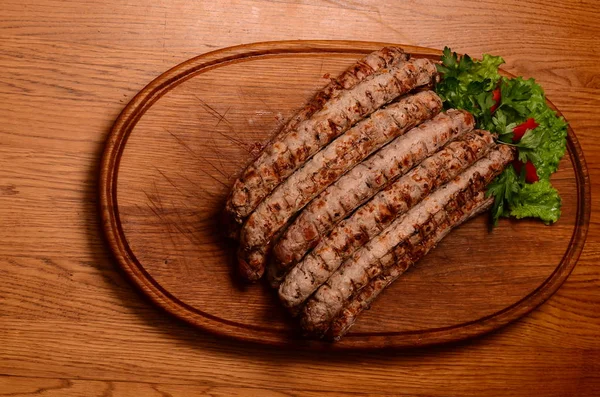 Salsichas grelhadas saborosas em tábua de madeira — Fotografia de Stock