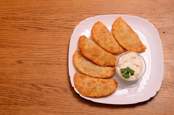 Uzbek eastern Tatar cuisine, cheburek with meat and suluguni cheese in a white plate with vegetables and greens on a wooden table. — Stock Photo, Image