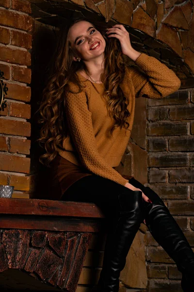 attractive young woman sitting in chair near fireplace in studio