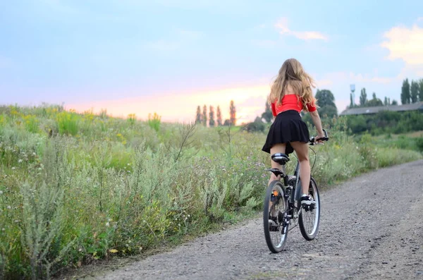 Hermosa chica montar en bicicleta en los campos al atardecer Ucrania Lutsk 03-08-2017 — Foto de Stock