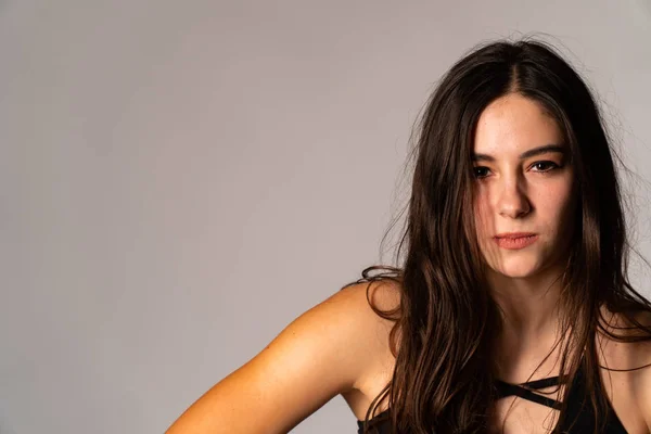 Portrait of disconcerted young woman in light clothes looking aside covering nose with hand isolated on white wall background in studio. People sincere emotions, lifestyle concept. Mock up copy space