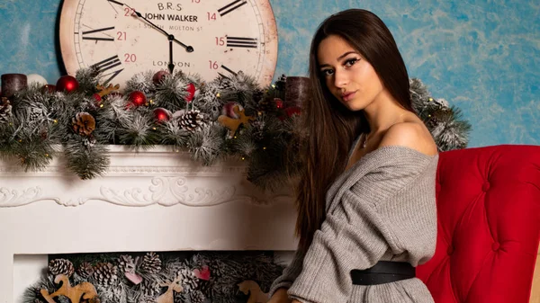 크리스마스 스튜디오의 벽난로 근처에 포즈를 취하고 스웨터를 아름다운 — 스톡 사진