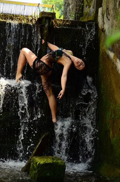 Unga brunett modell poserar mot ett vattenfall — Stockfoto