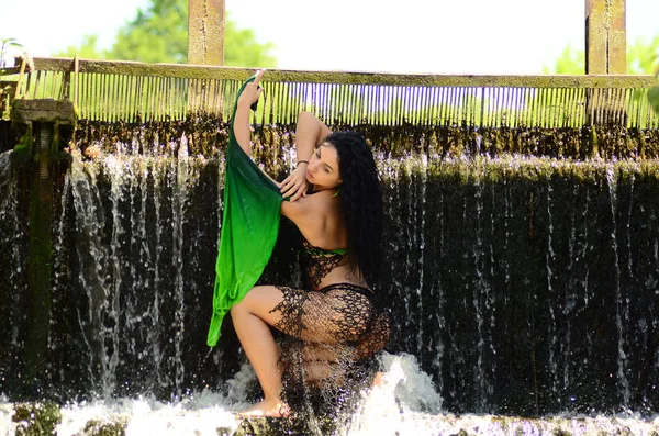 Young brunette model posing against a waterfall — Stock Photo, Image