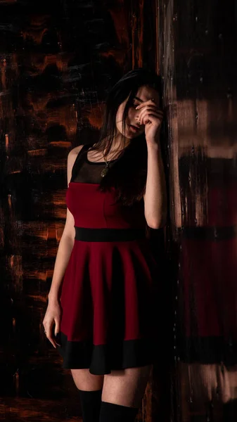 可愛いです若いですセクシーモデル女性とともに黒髪で赤いドレスポーズでダークスタジオ — ストック写真