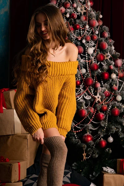 美しいブルネット若い女性がクリスマスの装飾されたスタジオで暖炉の近くにポーズ — ストック写真