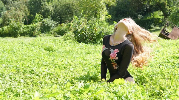 Portret van een jonge glimlachende blonde vrouw liggend op groen gras. — Stockfoto