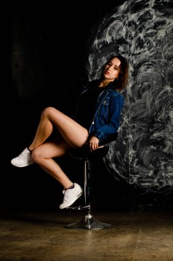 Güzel genç bir kadın karanlık arka planda poz veriyor. 