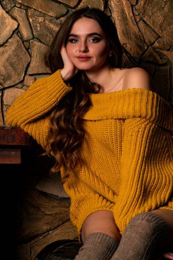 Güzel kız, şöminenin yanında poz veriyor.   