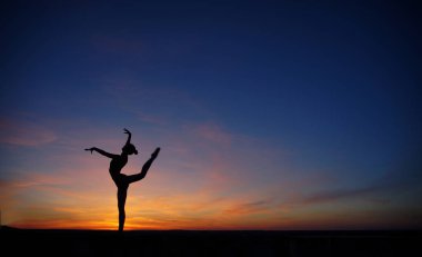 Dans eden dansçı gün batımına karşı havada yarılır.