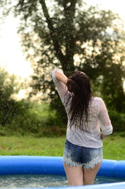 Gün batımında, havuzda ıslak güzel bir kız bedeni.