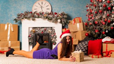 Noel süslemeli stüdyoda şöminenin yanında poz veren çekici esmer kadın.  