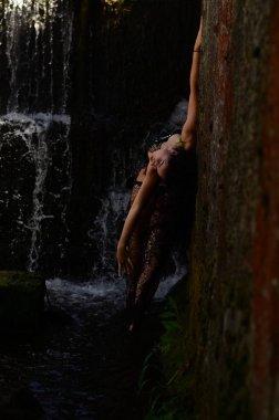 Genç esmer model bir şelale karşı poz