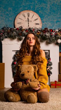 Noel süslemeli stüdyoda şöminenin yanında poz veren güzel esmer genç bir kadın. 