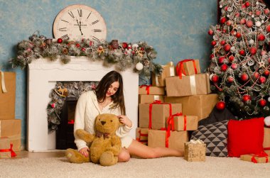 Noel süslemeli stüdyoda şöminenin yanında poz veren çekici esmer kadın.  