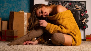 Noel süslemeli stüdyoda şöminenin yanında poz veren güzel esmer genç bir kadın. 