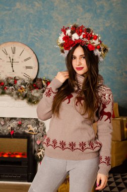 Noel süslemeli stüdyoda şöminenin yanında poz veren çekici esmer kadın.  