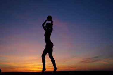 Dans eden dansçı gün batımına karşı havada yarılır.