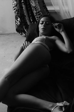 İç çamaşırlarıyla kanepede poz veren sevimli, çekici, çekici bir kızın portresi. 