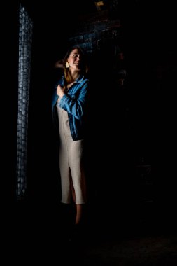 esmer kız yeşil bir ceket ve beyaz tuğla duvarın yanında sutyen standları.