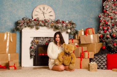 Noel süslemeli stüdyoda şöminenin yanında poz veren çekici esmer kadın.  