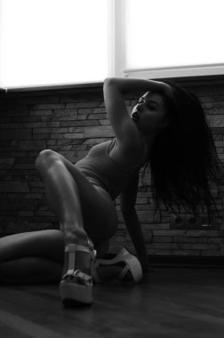 Genç, zayıf, seksi ve çekici esmer kadın pencerenin önünde siyah iç çamaşırlı.