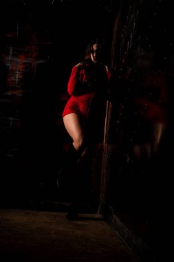 Koyu arkaplanda kırmızı kazaklı, güzel, çıplak kadın.   