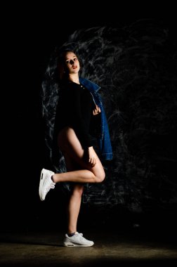 Güzel genç bir kadın karanlık arka planda poz veriyor. 