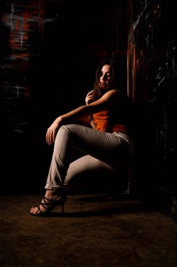 Güzel esmer model, karanlık odada poz veriyor. 