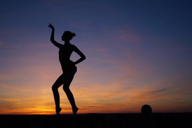 Dans eden dansçı gün batımına karşı havada yarılır.