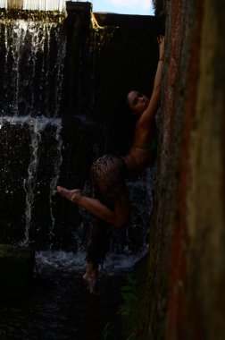 Genç esmer model bir şelale karşı poz