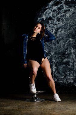 Güzel genç bir kadın karanlık arka planda poz veriyor. 