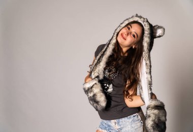 Güzel esmer manken şık kıyafetler içinde, aydınlık odada poz veriyor. 