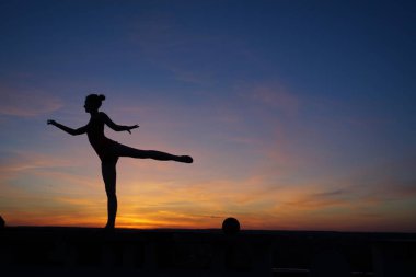 Dans eden dansçı gün batımına karşı havada yarılır.