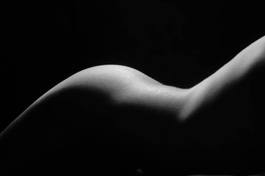 Siyah ve beyaz güzel kadın vücudu. Üzerinde gölgesi olan zarif çıplak bir kadının moda sanat stüdyosu portresi. Kadın midesi siyah arka planda izole edilmiş. Erotik poz düşük tuş atışı.