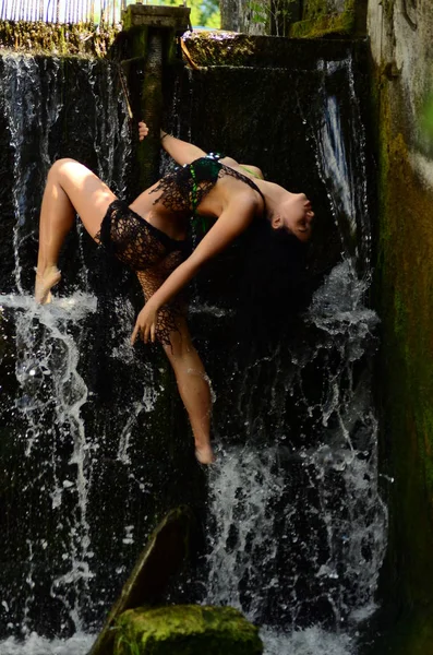 Young brunette model posing against a waterfall — Stock Photo, Image
