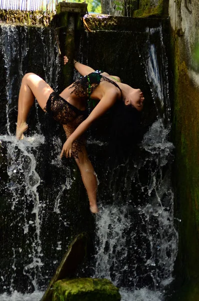 Joven modelo morena posando contra una cascada — Foto de Stock