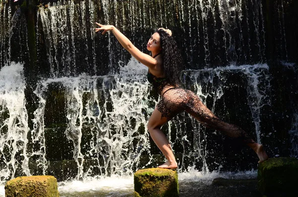 Joven modelo morena posando contra una cascada — Foto de Stock