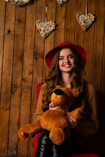 beautiful brunette woman with toy bear posing in wooden studio