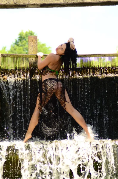 Jonge brunette model poseren tegen een waterval — Stockfoto