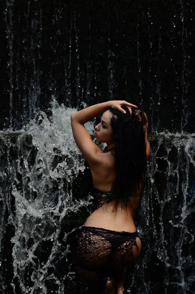 Jeune modèle brune posant contre une cascade — Photo