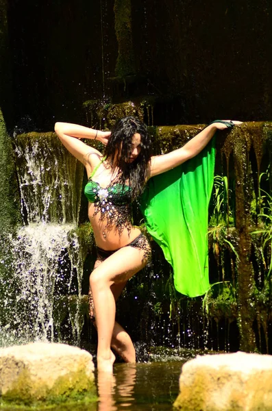 Young brunette model posing against a waterfall